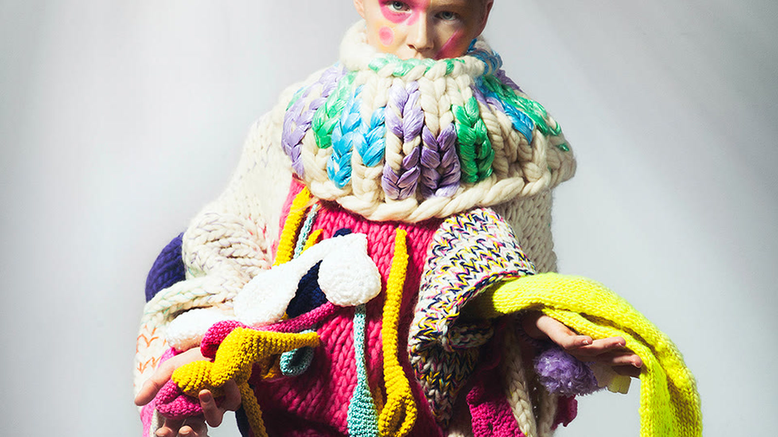 Sculptural knitwear combining large vertical loops, horizontal rows, and contrasting stitch scales