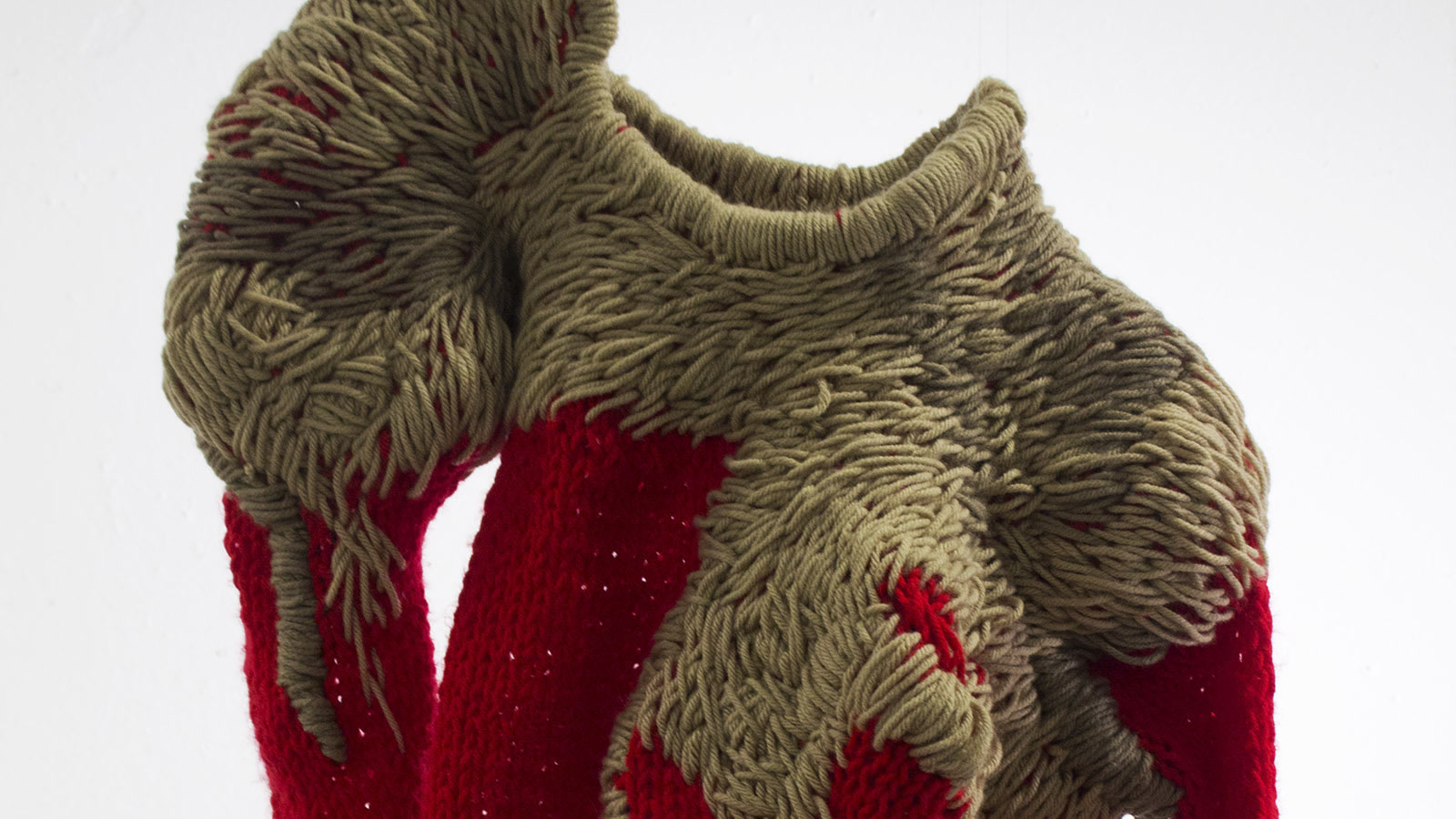 Studio scultoreo in maglia rossa e kaki con campi colore a contrasto e struttura ad anse visibile