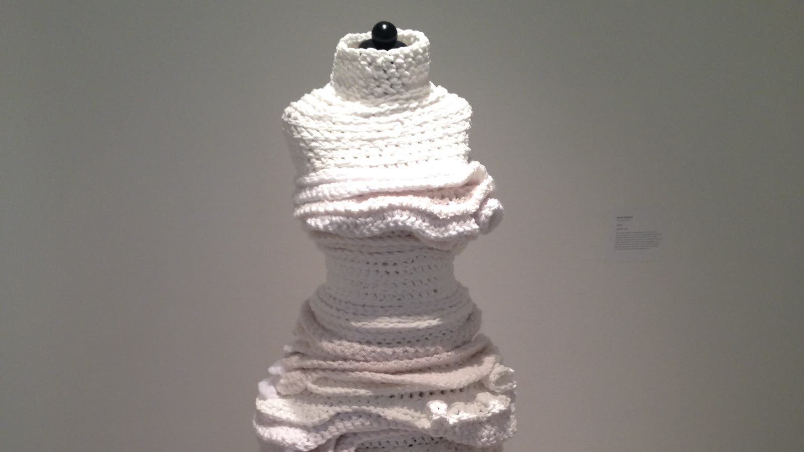 White sculptural knitted form arranged in compressed and released horizontal volumes