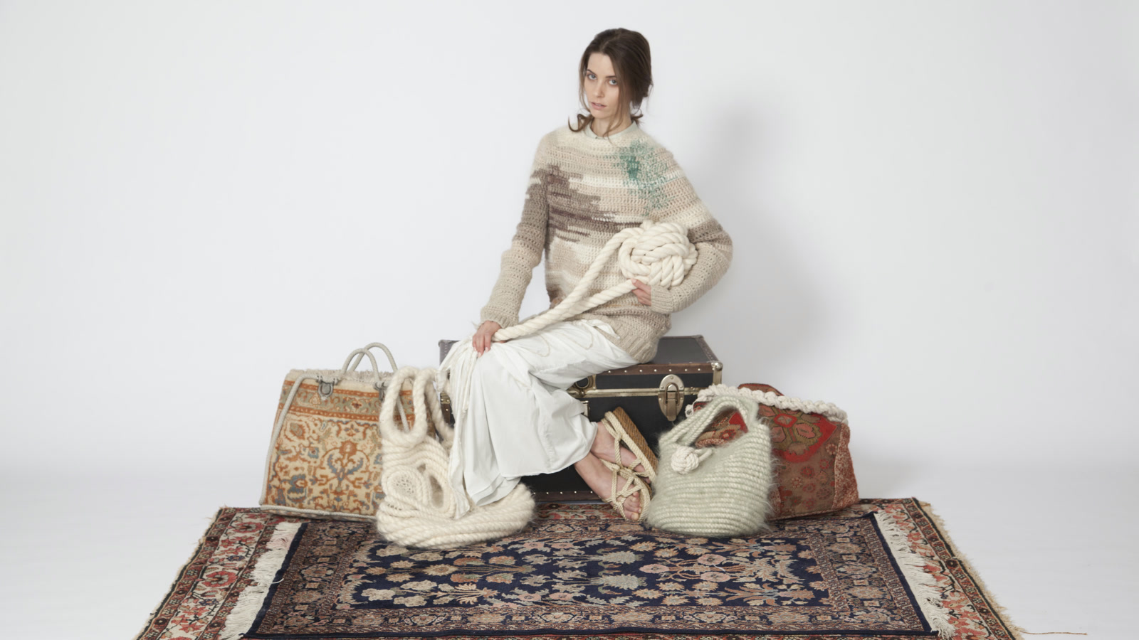 Model seated in a striped hand-knit sweater among rope-constructed textile accessories