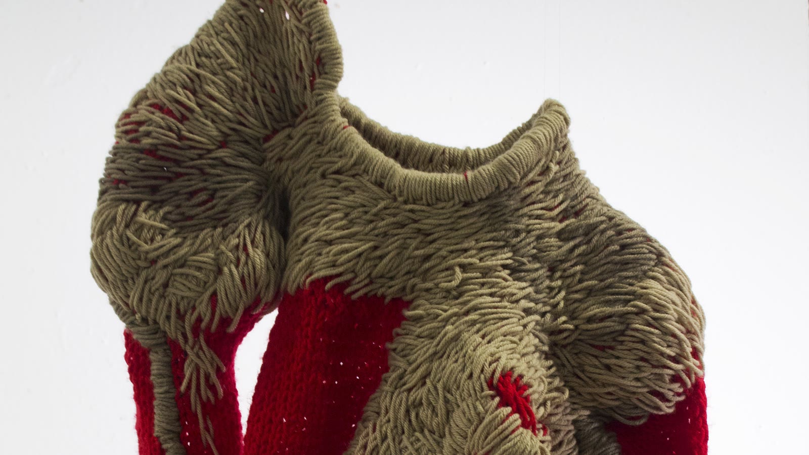 Close view of taupe and red knitted structures showing varied yarn paths and loop formations